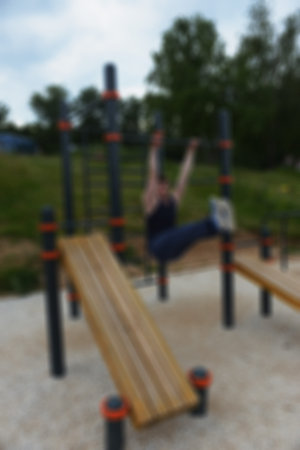 Sport- training outdoors in summer park. Workout young man performs exercise. Blurred background - a...