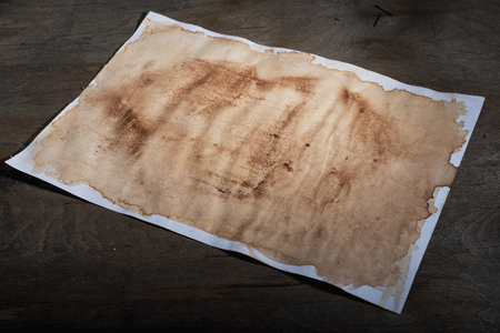 A sheet of paper with the effect of aging on dark wooden background.の写真素材