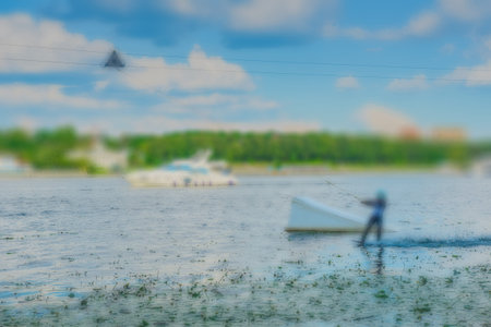 Summer blur background- professional wakeboarding is an extreme water sport. The athlete moves on the board on the water surface with traction, performs the various elements of slalom, jumps, flips.の写真素材