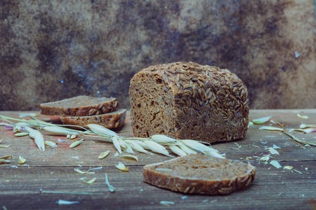 Natural background- rustic mood. Still life: sheaf of oats, sliced brown breadの写真素材