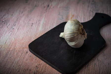 Still life- preparation of the sliced garlic. On a dark background lies the husk of seasoning. The...