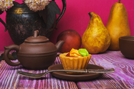Art still life. Composition-clay teapot and cups. Sweet fruit. Beautiful flowers