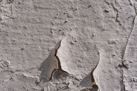 Destroyed plaster on the wall. Numerous cracks, chips and peeling paint. Texture- damaged materialの写真素材