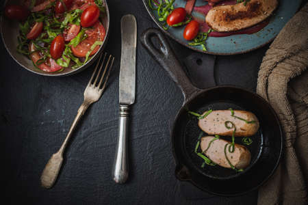 Unusual spaghetti with sausages and seasoning in a plate. Decorates pasta with fresh vegetables. Kitchen utensilsの写真素材