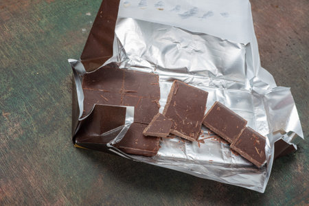 Packaging of chocolate. Pieces of sweets are lying on a wooden table- flat lay