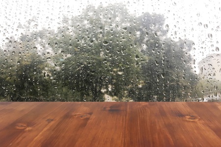 Empty wood table top ready for your product display montage. with rain drop on window backgroundの写真素材