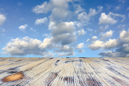 old painted washed oak wood table on the blurry blue sky clouds background, wooden table