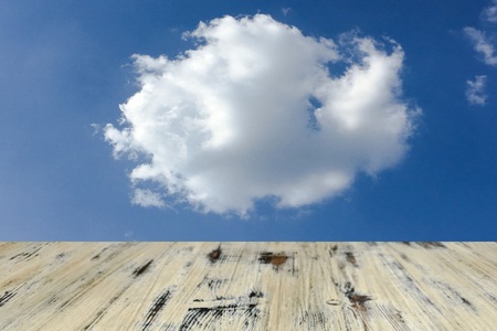 old painted washed oak wood table on the blurry blue sky clouds background, wooden tableの写真素材
