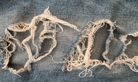 Ripped denim jeans background. Texture of denim or blue jeans background