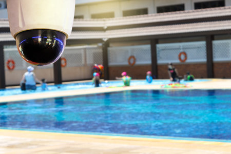 CCTV monitoring against blur of people at a swimming pool background.