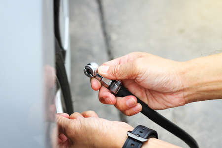 Close up a man hand holding Tire inflation head for checking air pressure and filling air in the tires of car.の写真素材