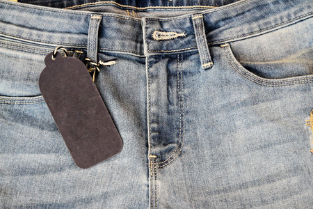 Blank black price tag in jeans pocket, closeup. Space for text