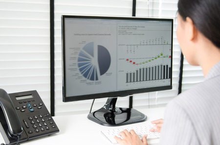 Close up business woman working in office with business graph on computerの写真素材