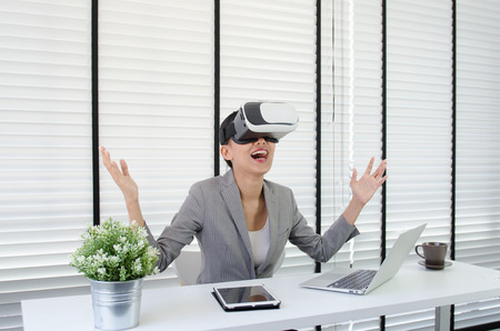 Asian woman use virtual reality glasses ( VR ) in her officeの写真素材