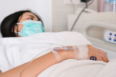 Close up young woman patient lay on bed in hospital with intravenous normal salineの写真素材