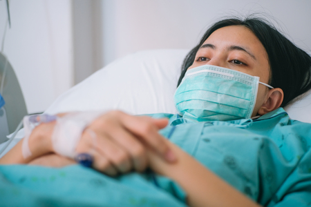 Close up young woman patient lay on bed in hospital with intravenous normal salineの写真素材