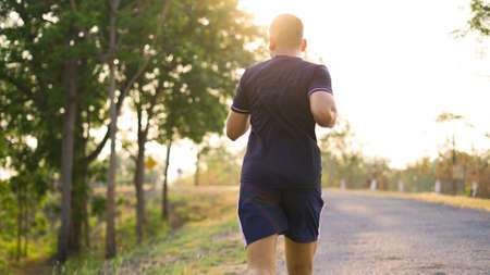 Sporty teenage boy running on natural park road with sunset time.の写真素材