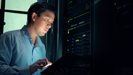 System administrator using digital tablet while working in data center.
