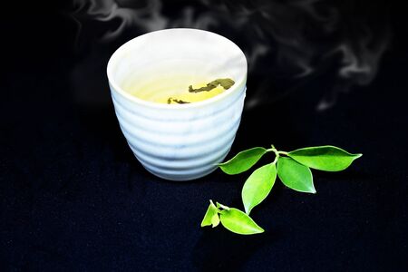 Hot tea in a white cup, put on a black background.の写真素材