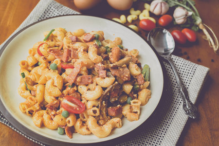 fried macaroni with egg pork ham and vegetable in tomato sauce in plate placed on a wooden table : Vintage Styleの写真素材