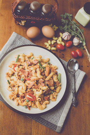fried macaroni with egg pork ham and vegetable in tomato sauce in plate placed on a wooden table : Vintage Styleの写真素材