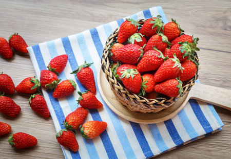 Fresh Strawberry in wicker basket Decorated with blue clothon brown wooden background;Vintage style.の写真素材