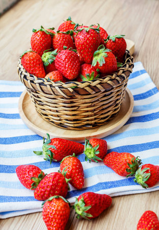 Fresh Strawberry in wicker basket Decorated with blue clothon brown wooden backgroundの写真素材