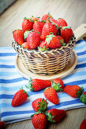 Fresh Strawberry in wicker basket Decorated with blue clothon brown wooden background;Vintage style.の写真素材