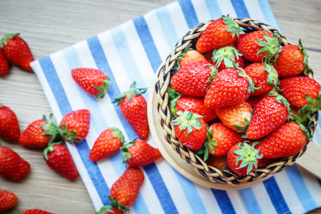 Fresh Strawberry in wicker basket Decorated with blue clothon brown wooden background;Vintage style.の写真素材