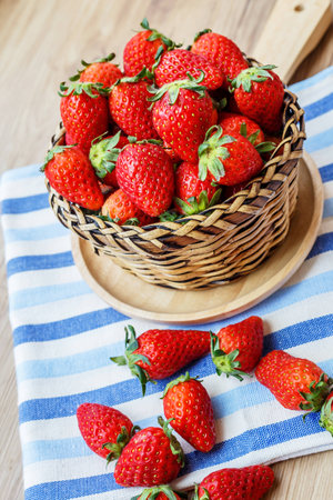 Fresh Strawberry in wicker basket Decorated with blue clothon brown wooden background;Vintage style.の写真素材