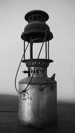 black and white picture of vintage kerosene oil lantern lamp in an antique rustic country barn with aged wood floorの写真素材
