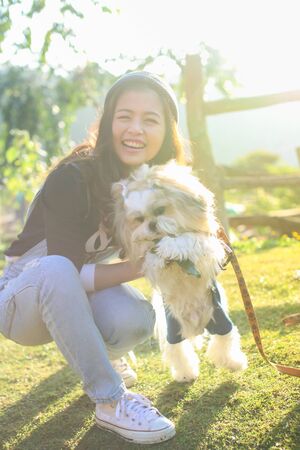 Happy woman with Shih Tzu in the park, Young woman playing with her Shih Tzu dog. concept aout animals and peopleの写真素材