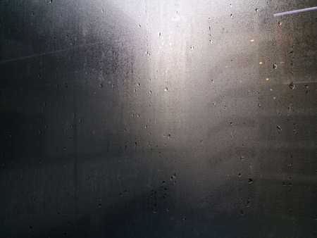 The morning sun shines through the clear glass of the window, sees the water droplets after the rain, the background is the building.の写真素材