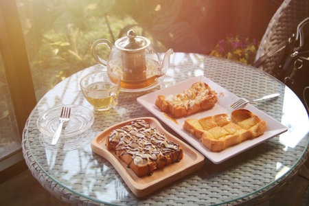the afternoon hot tea with honey toast and whip cream on wood plate on table in the garden