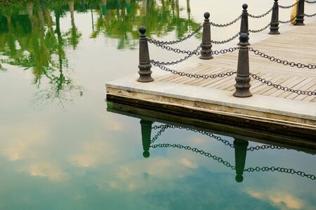 Railing posts of lake shore and its reflection over waterの写真素材