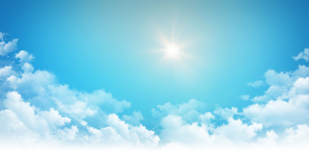Sunlight shining high in blue sky, above white cloudsの写真素材