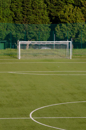 A soccer goal stands empty on a neatly trimmed field, with lush greenery in the background under...