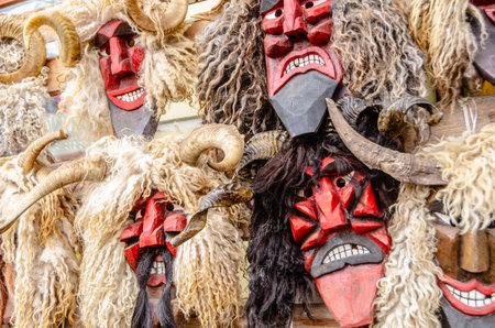 A row of masks with horns and red faces. Some of the masks have horns and some do not
