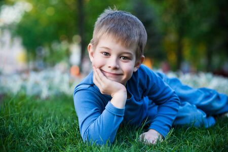 cheerful little boy laying on the green grassの写真素材