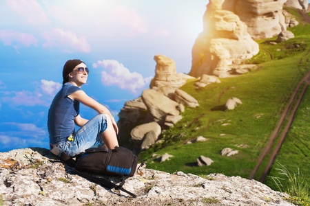 young girl is resting sitting on the grass in the mountainsの写真素材