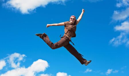jumping girl with hands up against  blue skyの写真素材