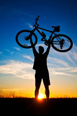 cyclist with a bike silhouette on a blue skyの写真素材