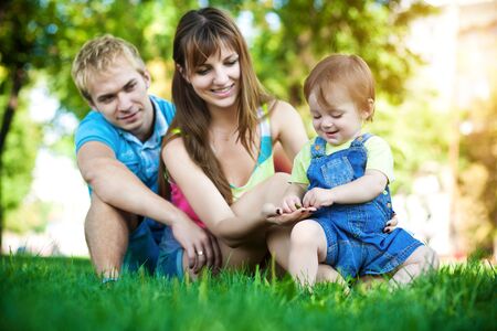parents with baby in a greenl summer parkの写真素材