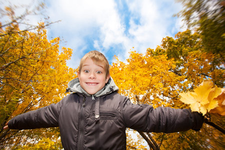 happy cheerful kid on a background of sky and autumn trees