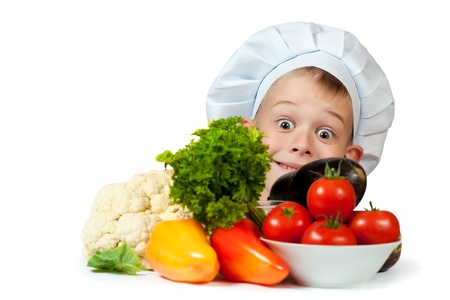 cute chef boy is hiding behind a vegetables  isolatedの写真素材