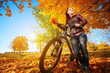woman with bike on a autumn leafs backgroundの写真素材
