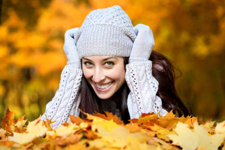 pretty woman is lying in a yellow autumn leavesの写真素材