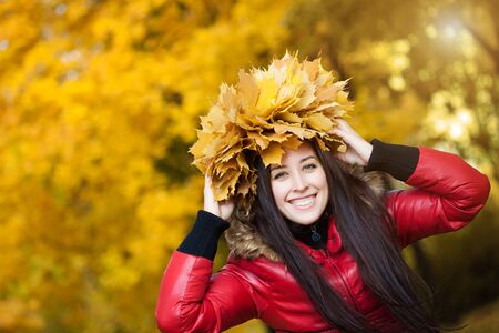 happy  woman in a wreath of yellow autumn leavesの写真素材