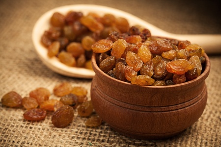 Raisins on a wooden spoon on a burlapの写真素材