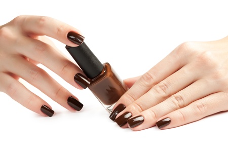 Hands with brown manicure and nail polish bottle isolatedの写真素材